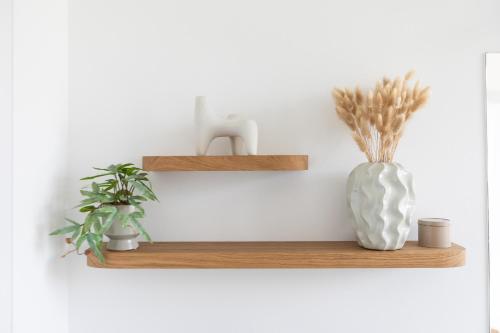 a wooden shelf with a vase and two plants at Stay Cozy - Apartment am See mit Pool und Sauna in Bad Saarow