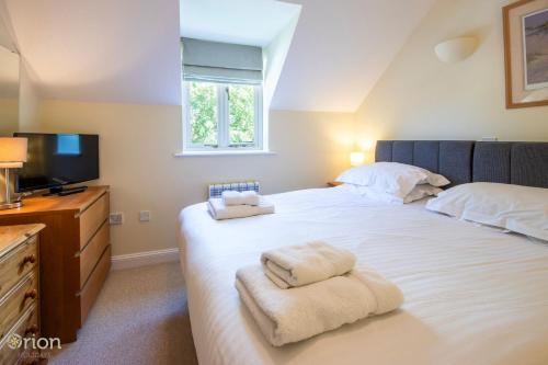 a bedroom with a large white bed with towels on it at Mill Village 66, Damsel Cottage - P in Somerford Keynes