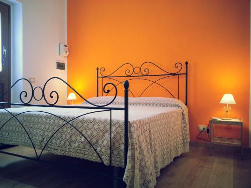 ein Schlafzimmer mit einem Bett mit einer orangefarbenen Wand in der Unterkunft Il Piccolo Baglio in Valderice