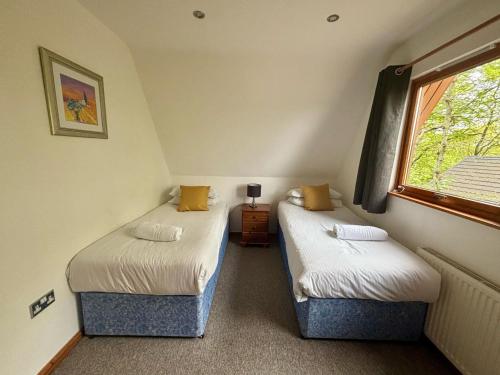 two twin beds in a room with a window at Acorn Lodge in Newton Abbot