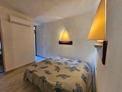 a bedroom with a bed and a lamp on the wall at Pgs Immobiliare srls Villetta Smeralda Villetta immersa nella natura con parcheggio privato e WIFI in La Maddalena