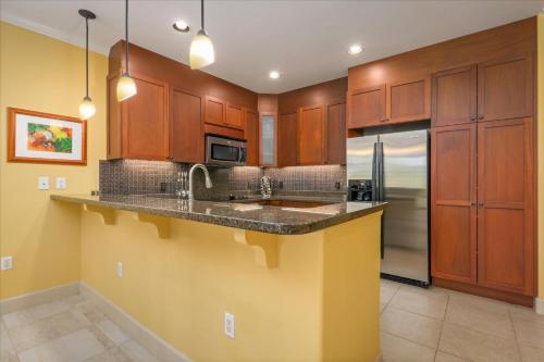 a kitchen with wooden cabinets and a sink and a refrigerator at Hale Pikake in Hapuna Beach