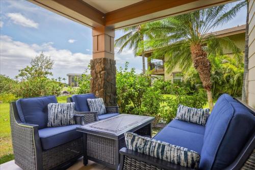 a porch with chairs and a table and a palm tree at Hale Pikake in Hapuna Beach