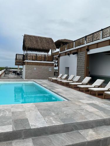 a swimming pool with lounge chairs next to a building at Hotel Mundo Maya Tulum Aeropuerto in Tulum