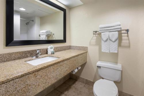 un bagno con lavandino, water e specchio di Best Western Gateway To The Keys - Florida City, Homestead, Everglades a Florida City
