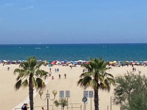 a group of people walking on a beach with umbrellas at SoleeMare Barletta in Barletta