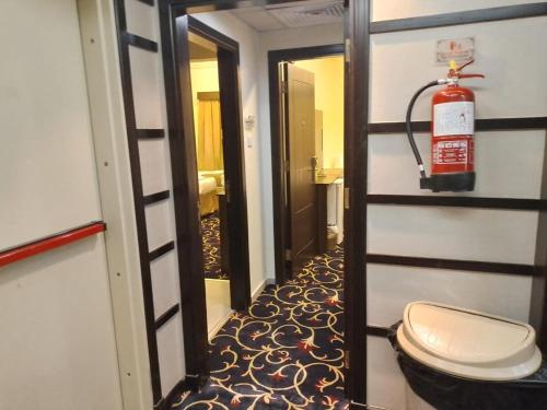 a bathroom with a toilet and a fire extinguisher at فندق نزهة المشتاقين in Al Gharīth