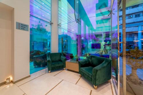 two green chairs in a room with a window at Hotel Manorama Vijayawada in Vijayawāda