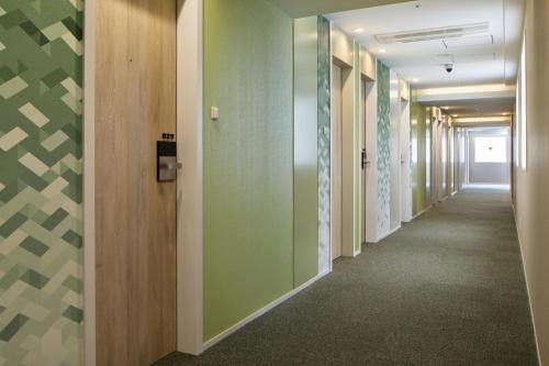 a corridor in an office building with green walls at Holiday Inn & Suites Sapporo Odori Park by IHG in Sapporo