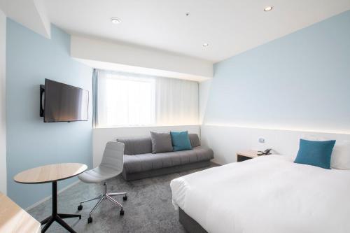 a hotel room with a bed and a couch at Holiday Inn & Suites Sapporo Odori Park by IHG in Sapporo