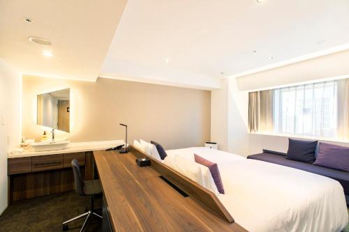 a bedroom with a bed and a desk and a sink at Holiday Inn & Suites Sapporo Odori Park by IHG in Sapporo