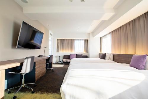a hotel room with two beds and a flat screen tv at Holiday Inn & Suites Sapporo Odori Park by IHG in Sapporo