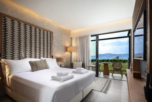 a bedroom with a white bed with a large window at La Mer Resort Spa Crete in Georgioupolis