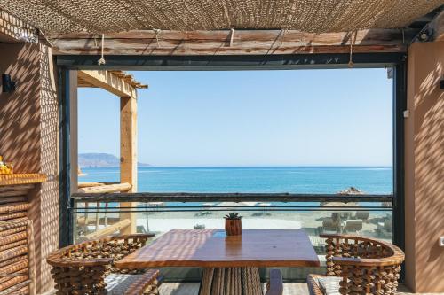 a table on a balcony with a view of the ocean at La Mer Resort Spa Crete in Georgioupolis