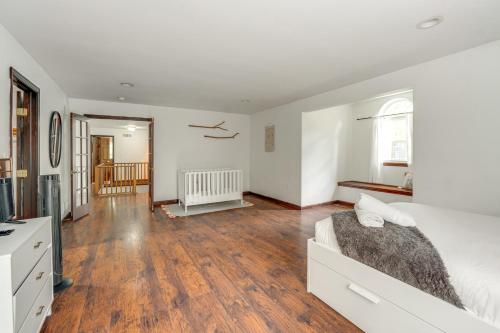 a white bedroom with a bed and a wooden floor at Family Home with Deck about 2 Mi to Camelback Mountain! in Tannersville