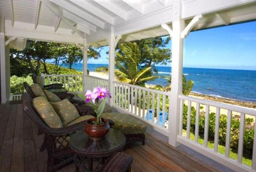 a porch with a couch and a table and the ocean at Holo Makani Beach House TVNC # 5141* in Hanalei