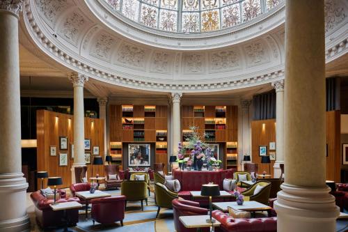 a lobby with chairs and tables in a building at Threadneedles, Autograph Collection in London