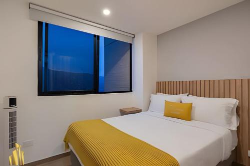 Un dormitorio con una cama con una ventana grande. en Class 48 Apt. 2604 - Vida moderna-vistas a la ciudad/AC, en Sabaneta