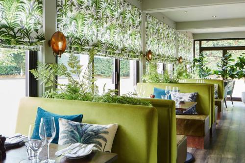 a restaurant with green chairs and tables and windows at Delta Hotels by Marriott Manchester Airport in Hale