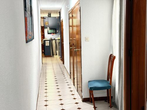 un corridoio con sedia blu e una cucina di Hostel Central Zaragoza a Saragozza