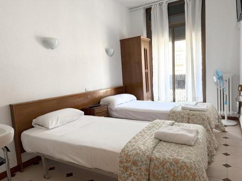 una camera d'albergo con due letti e una finestra di Hostel Central Zaragoza a Saragozza