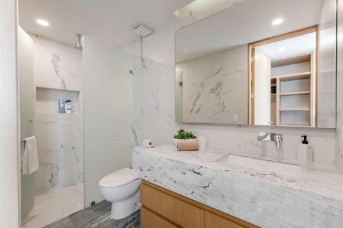 a white bathroom with a sink and a toilet at Luxurious 4BR condo by the beach - Rooftop pool in Cancún
