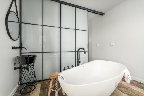 una bañera en un baño con una pared de cristal en Your Holidays Aquamarina Onyx 84, en Międzyzdroje