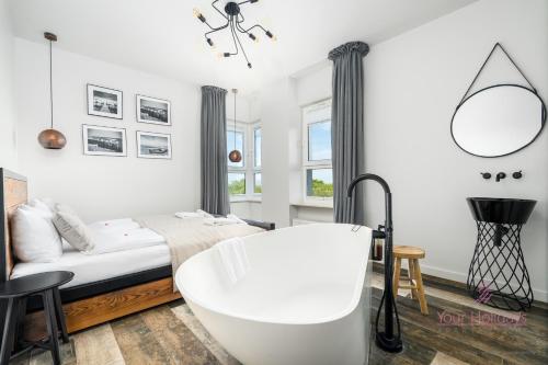 Un dormitorio blanco con bañera y cama. en Your Holidays Aquamarina Onyx 84, en Międzyzdroje