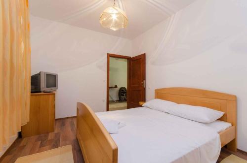 Un dormitorio con una cama blanca y un televisor. en Apartment in Tribalj 39244, en Tribalj