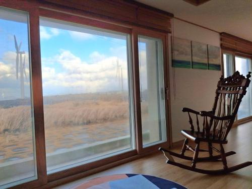 a rocking chair in a room with a large window at Jeju Noeul Bori Pension in Jeju
