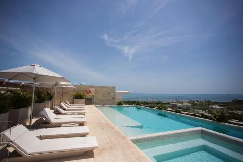 a swimming pool with lounge chairs and an umbrella at Luxurious 4BR condo by the beach - Rooftop pool in Cancún