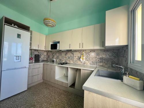 a kitchen with white cabinets and a white refrigerator at Villa daisy in Rafina
