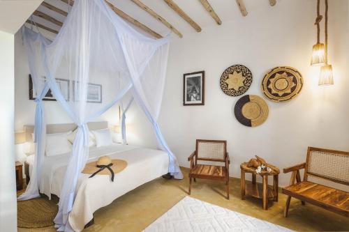 a bedroom with a canopy bed with a hat on it at Poa Poa Bungalows in Kiwengwa