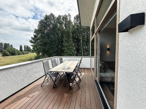 a wooden deck with a table and chairs on a balcony at Kooparc vakantiepark in Giesbeek