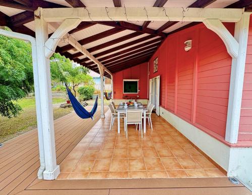 a deck with a table and chairs on a red house at Villa Ti Sable - Escale entre mer et nature in Saint-Pierre