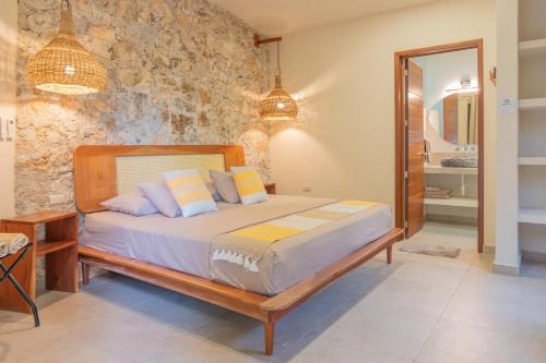 a bedroom with a bed and a stone wall at Casa Cactus Buenavista in Bacalar