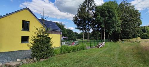 a yellow house with a tree in front of it at La Catiche in Bastogne