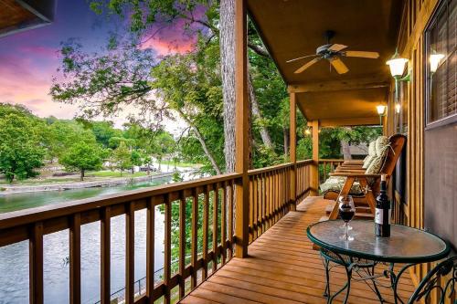 a porch with a table and a view of the water at Charming Green Riverfront Stay, New Braunfels in New Braunfels