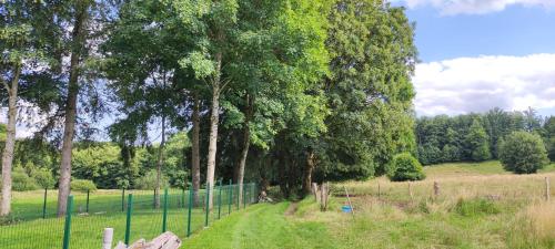 a fence in a field with trees in the background at La Catiche in Bastogne