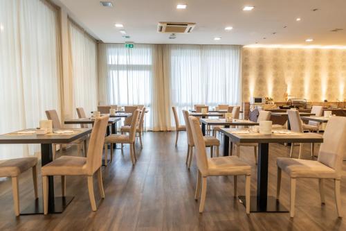 a dining room with tables and chairs and curtains at Hotel Majorca sul Mare in centro a Riccione con Area Fitness in Riccione