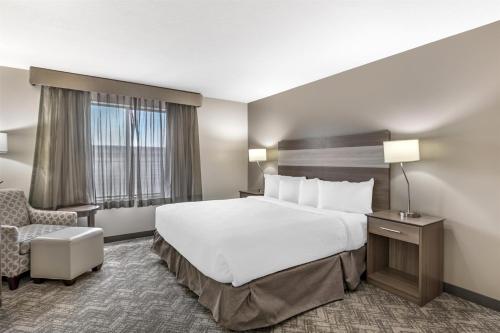 a hotel room with a large bed and a chair at Best Western Plus Great Northern Inn in Havre