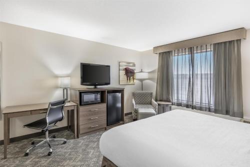 a hotel room with a bed and a desk and a tv at Best Western Plus Great Northern Inn in Havre