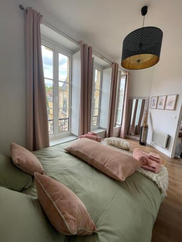 Cette chambre comprend un grand lit avec des oreillers et des fenêtres. dans l'établissement Au cœur du centre historique de Sarlat, à Sarlat-la-Canéda