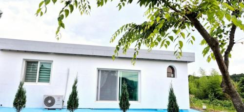 a white house with a pool in front of it at Namhae Sunset Pension in Namhae