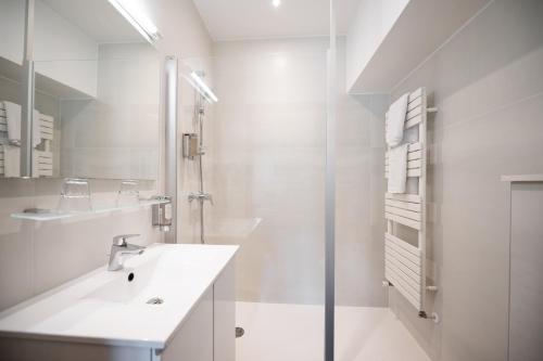 a white bathroom with a sink and a shower at Hôtel La Couleuvrine Sarlat Centre Ville in Sarlat-la-Canéda