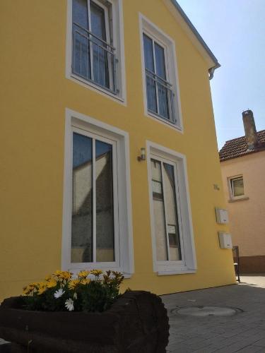 a yellow house with windows and flowers in front of it at Alte Heimat in Schwegenheim