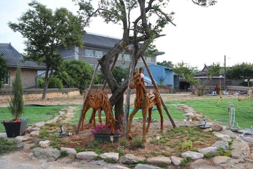 two sculptures of giraffes climbing a tree in a yard at Yeongam Nangjuwon in Yeongam
