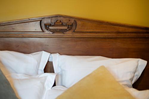 a bed with a wooden headboard and white pillows at Hôtel La Couleuvrine Sarlat Centre Ville in Sarlat-la-Canéda