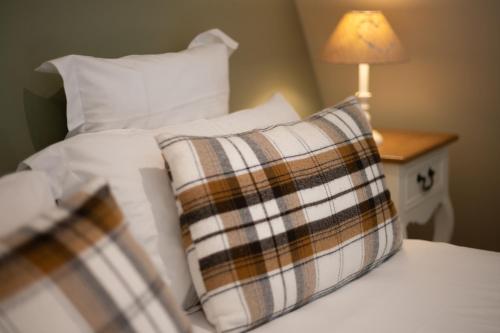 a bed with white pillows and a lamp on a table at Hôtel La Couleuvrine Sarlat Centre Ville in Sarlat-la-Canéda