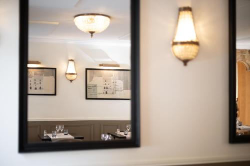 a mirror in a restaurant with lights on the wall at Hôtel La Couleuvrine Sarlat Centre Ville in Sarlat-la-Canéda